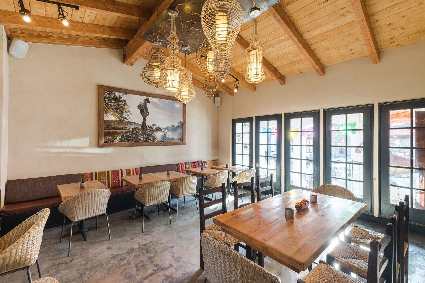 Tahona's warm, light-filled dining room with agave spirits along the wall